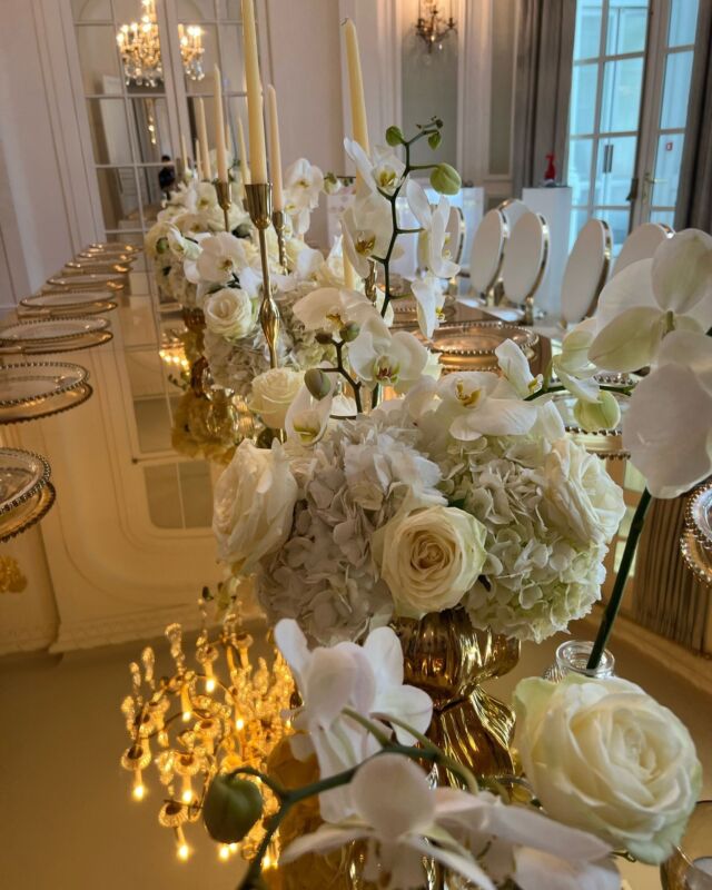 Elegant white floral table arrangement featuring delicate Colombian hydrangeas, pristine playa blanca roses, and exquisite Phalaenopsis orchids. The display includes a variety of vase arrangements, bud vases, and shimmering gold candles to complete the sophisticated look. #luxuryflowers #londonflowers #knightsbridge #roses #events